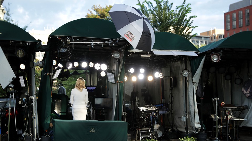 A Fox News anchor, shot from behind, delivers a broadcast into the camera. She's standing on "pebble beach," an area of the White House grounds where news networks set up their cameras for live shots.