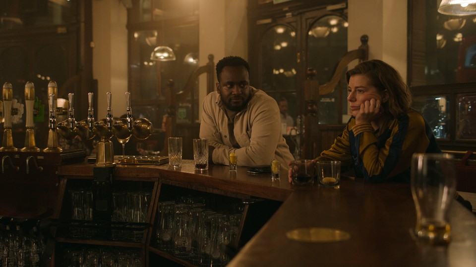 A still from the Apple TV+ series 'Slow Horses' showing two characters sitting at a bar