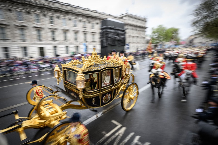 A gold-covered ornamental horse carriage is pulled along a parade route.