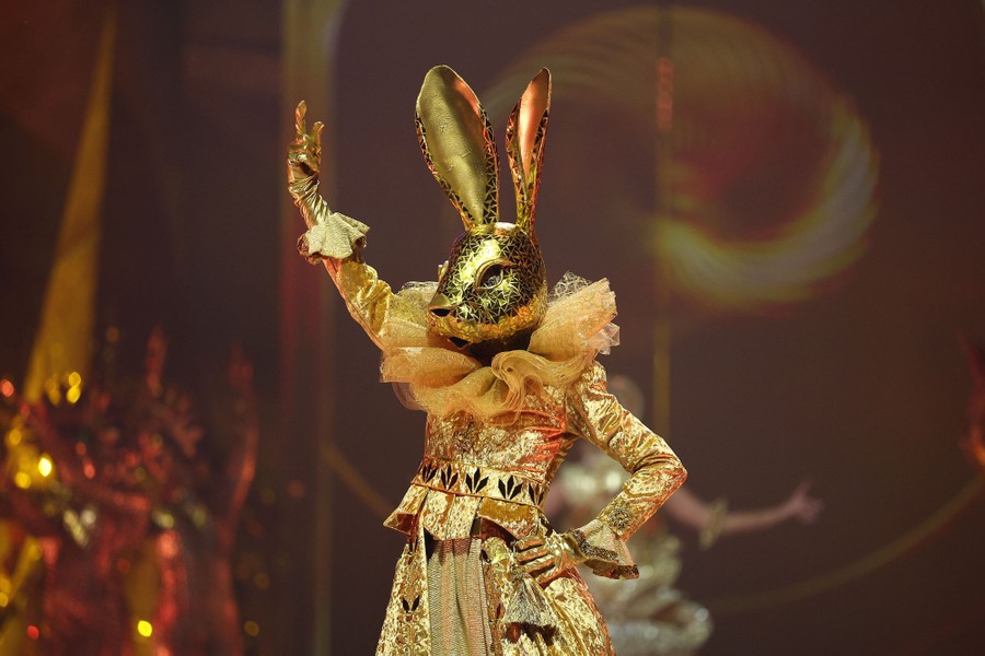A model wears a gold-colored costume and a shiny golden mask shaped like a rabbit's head.
