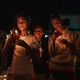 Family members of political prisoners hold photographs of their loved ones and candles during a nighttime vigil.