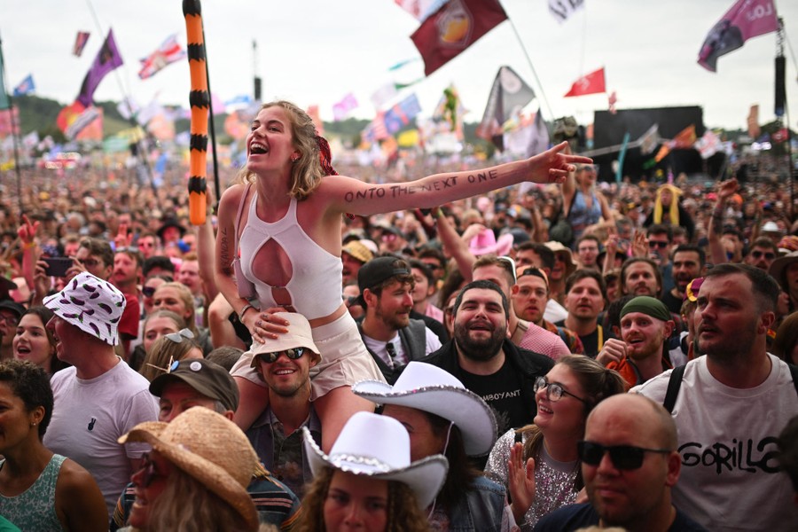 A crowd of concertgoers, with one woman sitting on someone's shoulders