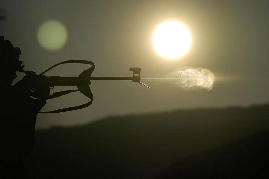 A silhouette of a person firing a rifle.