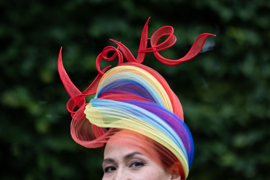 A woman wears a colorful, fancy hat, with ribbon on top that spells out the word "Love."