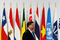 Xi Jinping stands in profile in front of international flags at a meeting of the G20 in 2019.