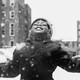 A girl lifts her face to the sky as snow falls.