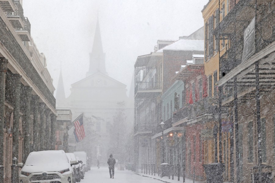 A person walks down a New Orleans street during a snowstorm.
