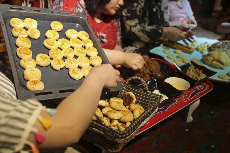 Several people prepare cookies while seated at a table.
