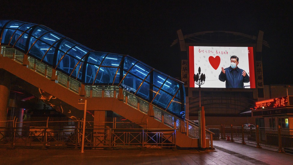 A large monitor shows an image of Chinese president Xi Jinping wearing a mask in an empty station.