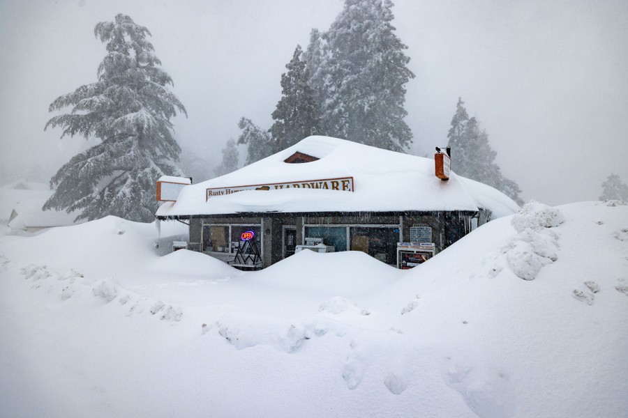 A small hardware store is covered in deep snow.