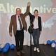 AfD top candidates Alexander Gauland and Alice Weidel hold hands in triumph in front of an AfD sign and balloons.