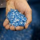 A hand holding a scoop of irregular blue plastic pellets, called nurdles