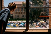 A student looks out of a window at an encampment protest.