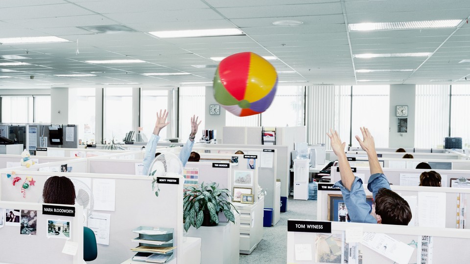 Workers throw a beachball in an office.