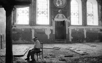 A man sits alone in a ruined synagogue in Russia.