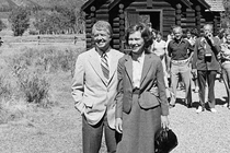 A black-and-white photo of Jimmy and Rosalynn Carter in front of a rural church and a small group of people