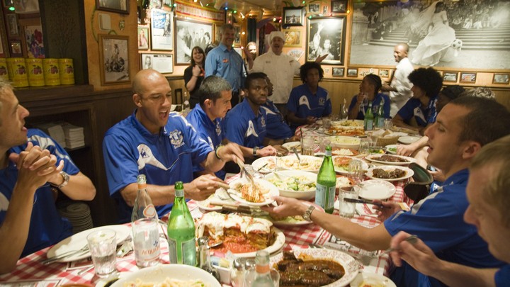 A soccer team eats a large spread at an Italian restaurant.