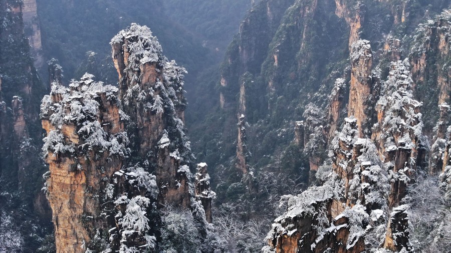 Steep, narrow rime-covered sandstone pillars stand in a valley.