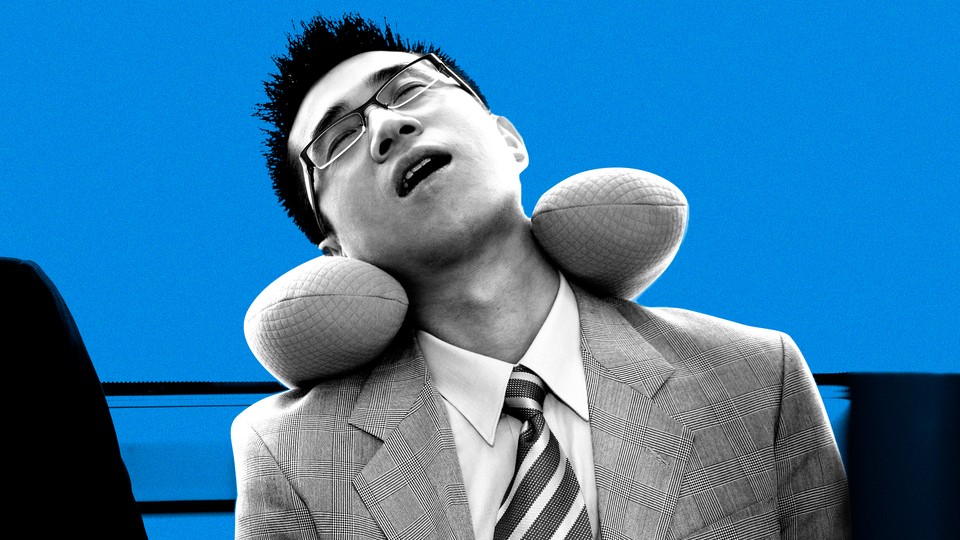 A businessman asleep on public transport using a neck pillow