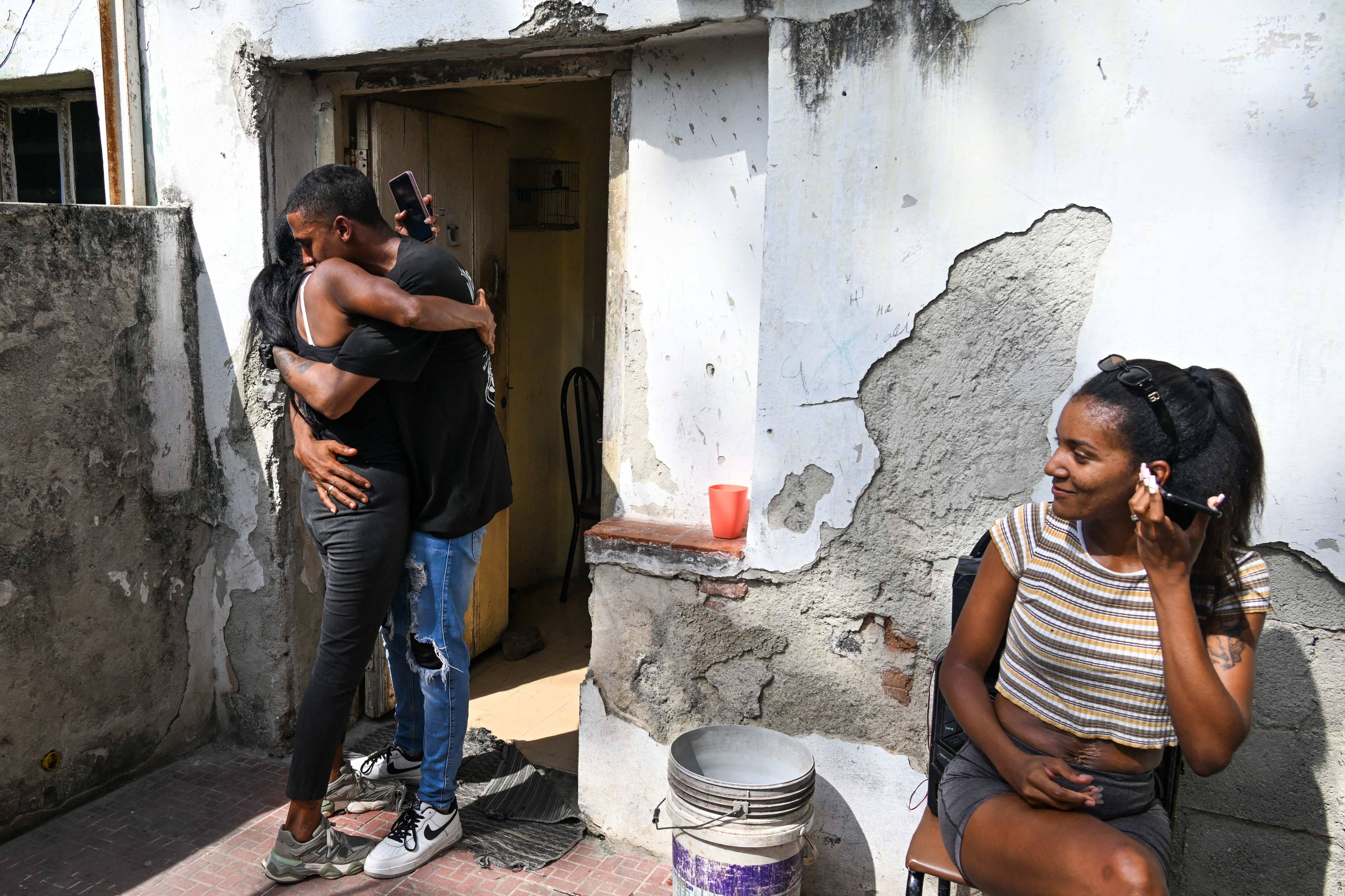 A man hugs his mother outside of a house.