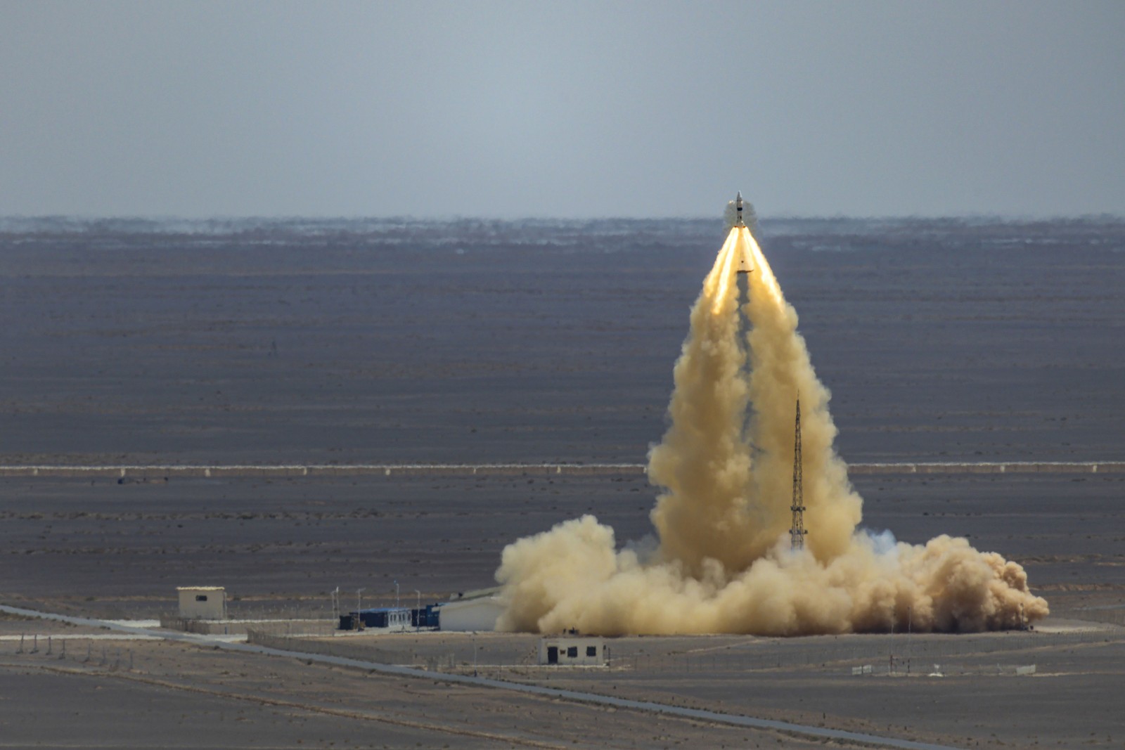 A test launch of a small spacecraft is seen in a desert setting.
