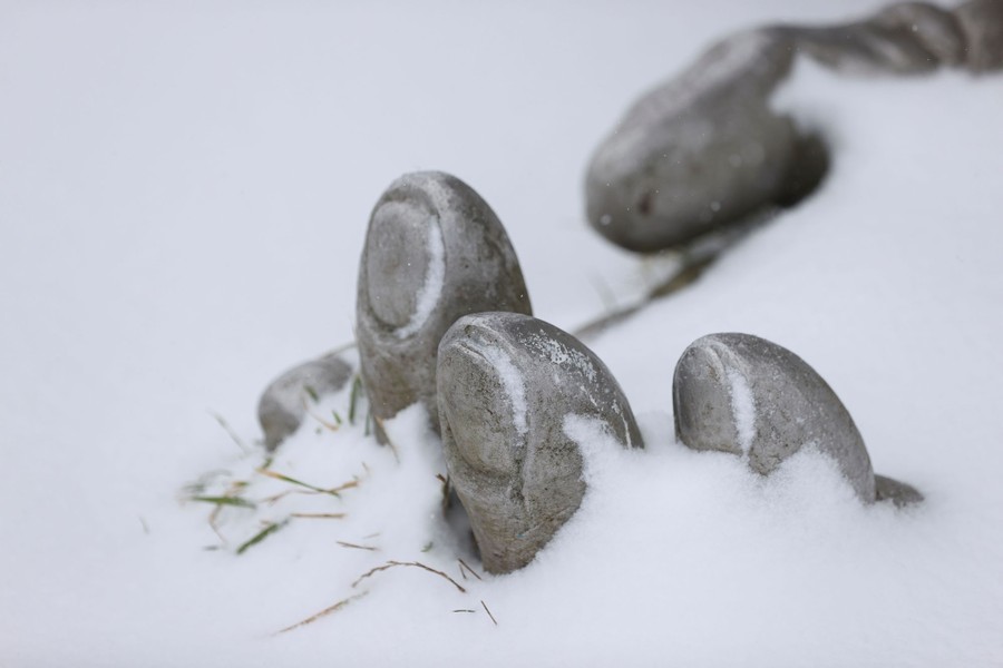 The fingers of a sculpture poke out of the snow.