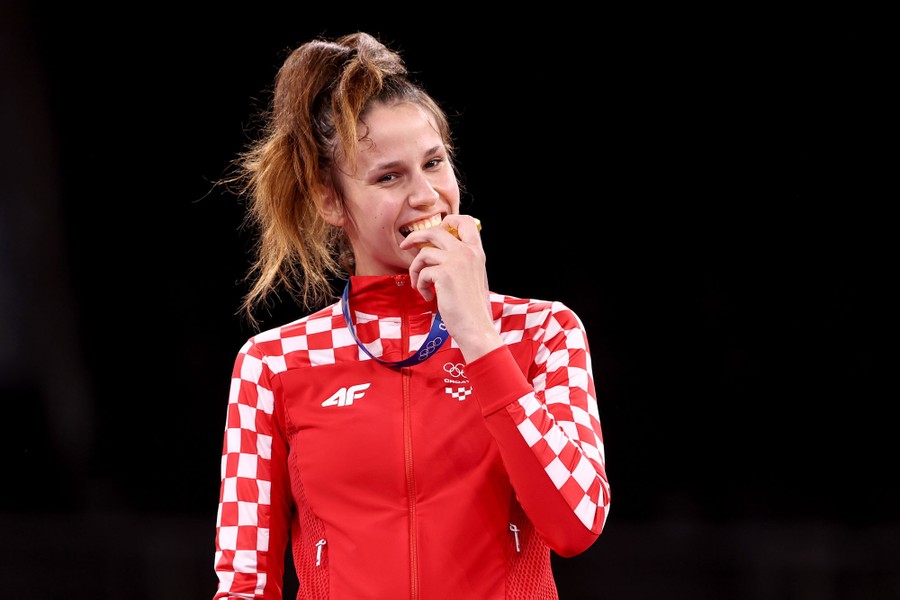 A winning athlete bites her medal while posing for a photo.