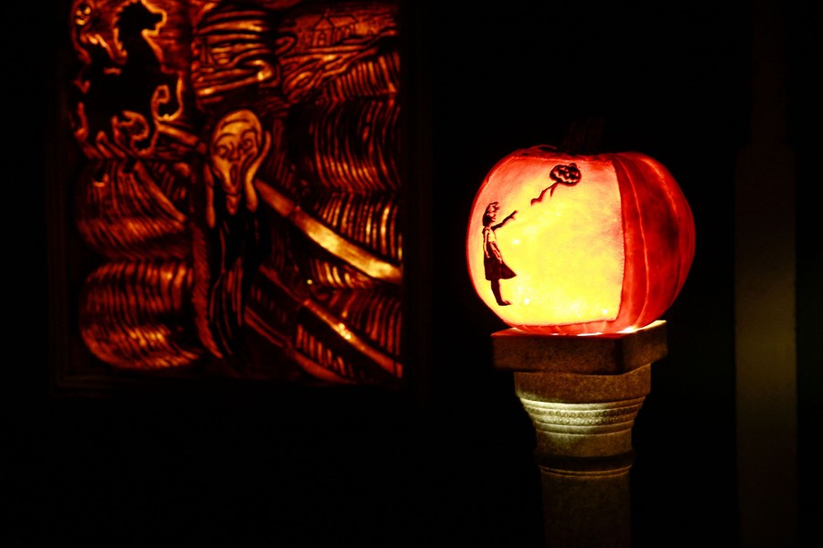 Pumpkins carved to resemble works of art are seen at night.