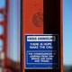 A blue and white sign attached to the Golden Gate Bridge that reads "There is hope, make the call"