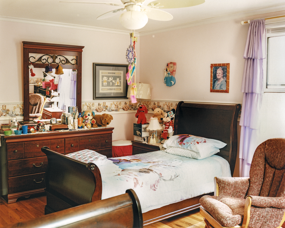 photo of cozy bedroom with dresser, mirror, neatly made twin bed, and toys
