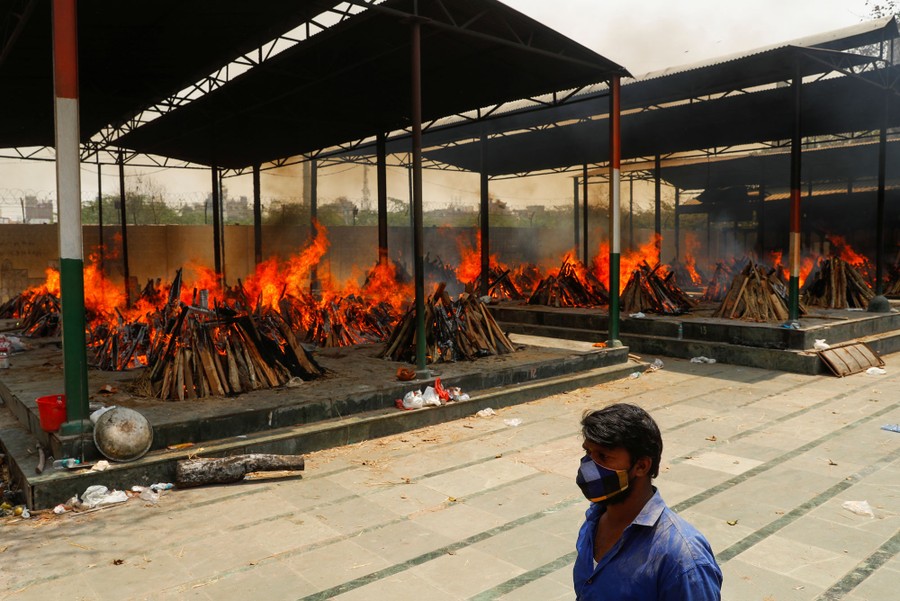 More than a dozen funeral pyres burn side by side in an open crematorium.