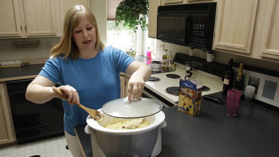 A woman cooks with a Crock-Pot in a kitchen.