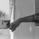 An imprisoned person stretches their arm out of a window.