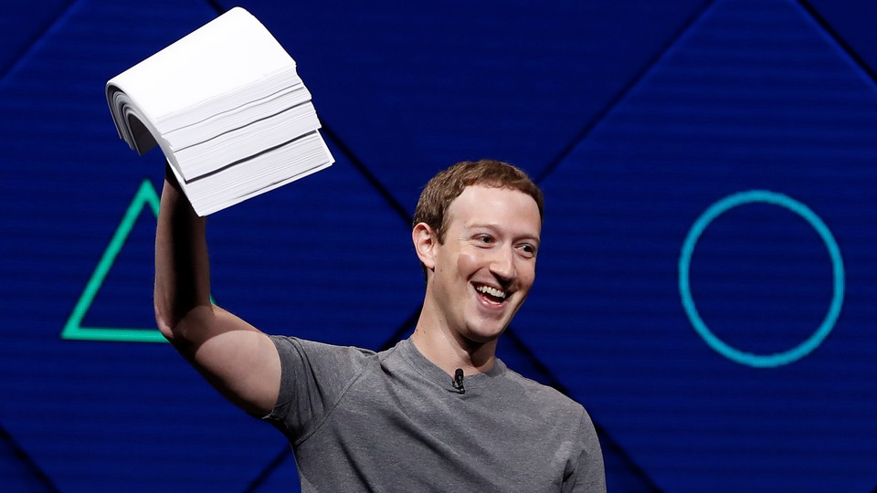 Mark Zuckerberg holds a stack of papers aloft, against a blue background.