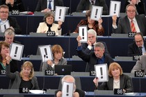 Men and women hold placards bearing an exclamation mark