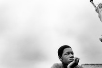 A boy sits near the Statue of Liberty.