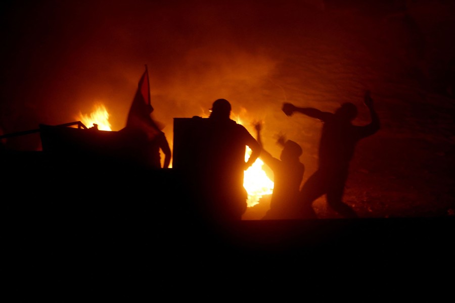 Protesters throw stones near a fire.