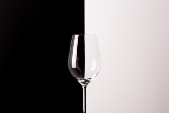 A photo of an empty wine glass in front of a black and white backdrop