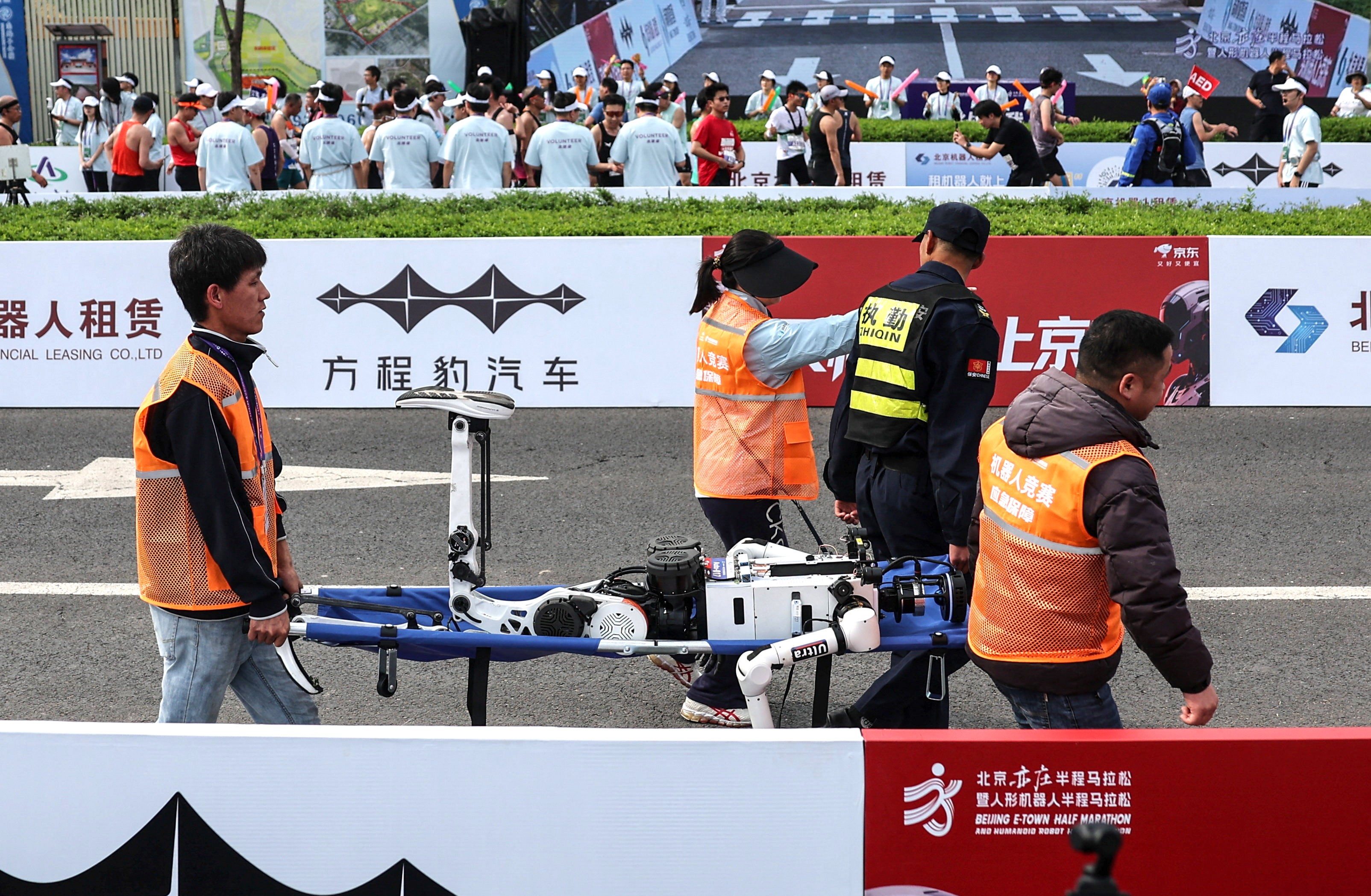 Staff members use a stretcher to carry a humanoid robot that crashed after a half-marathon.