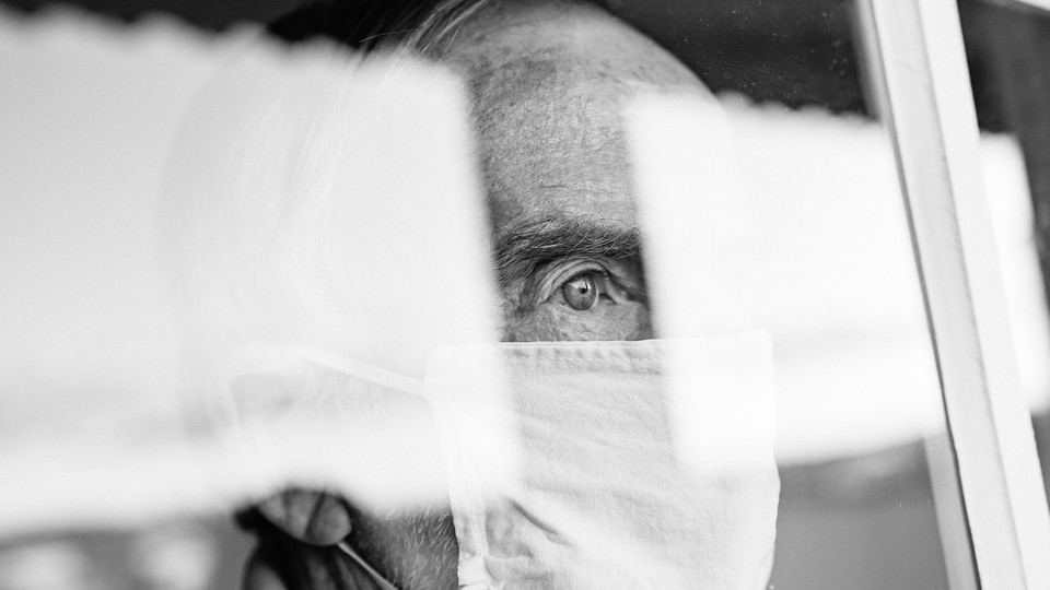 A photo of someone in a mask, looking out a window