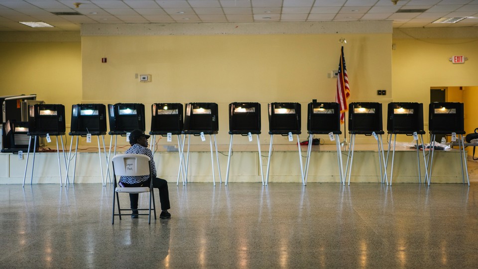 An election official sits in a chair while waiting for voters to arrive at a polling station in Miami, Florida, U.S., on Tuesday, March 17, 2020. Voters in Florida, Illinois and Arizona were trickling into the polls Tuesday as the coronavirus pandemic continued to wreak havoc on the Democratic presidential primary calendar with Ohio postponing its contest, citing a public health emergency.