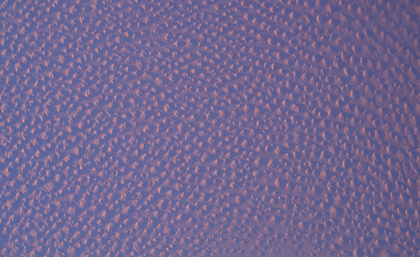 Low sunlight seen across dunes in the Sahara Desert, from high above