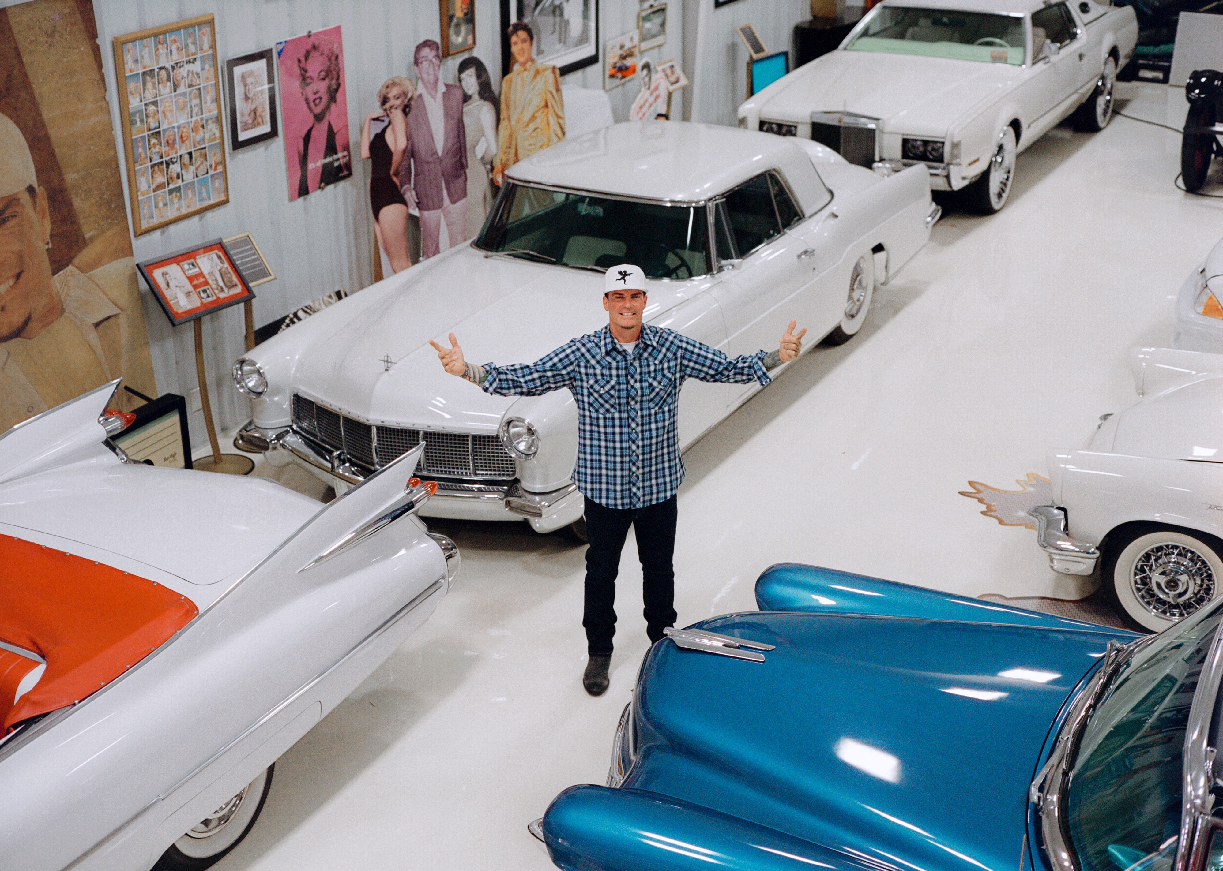 Vanilla Ice standing with his arms outstretched in his garage.