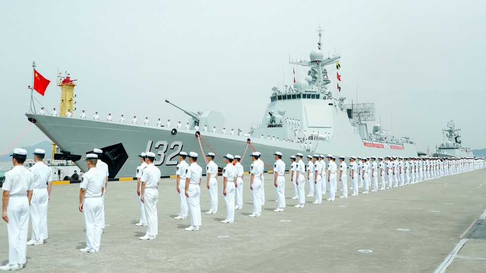 Members of the Chinese navy stand on the deck of a naval destroyer.