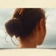 Image of the back of a girl's head as she looks towards the coast