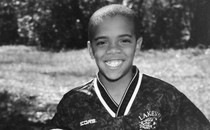 Writer Clint Smith, as a child, holding a soccer ball and grinning while wearing a jersey