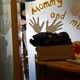 A teacher arranges a globe in a classroom. A sign reads "mommy and me" with handprints around the text. 