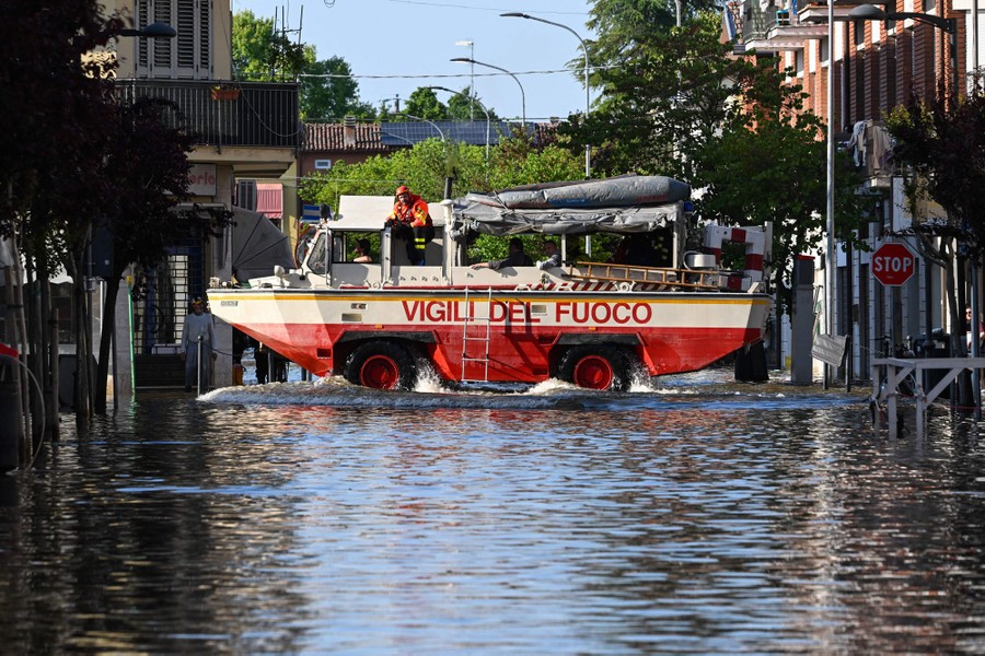 An amphibious rescue vehicle drives down a flooded street.