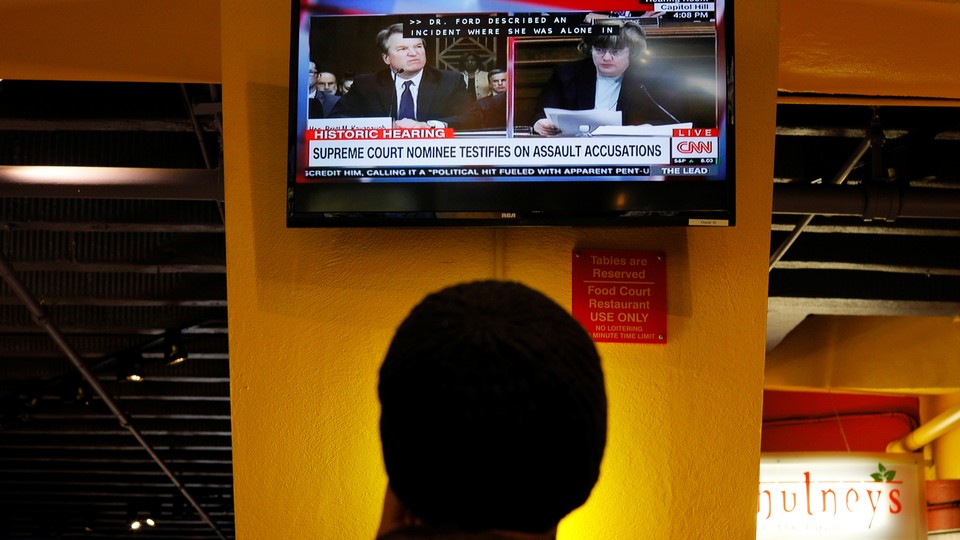 A person watches a television broadcast of the Kavanaugh hearing.