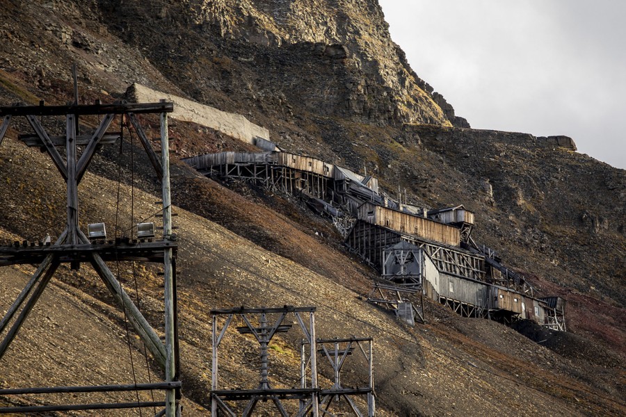 Abandoned mining structures stand on a mountainside.